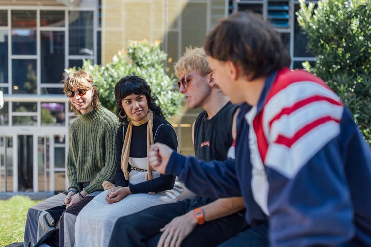 Four students sitting together on campus