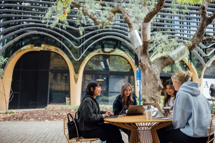 Four students sitting at a table on campus