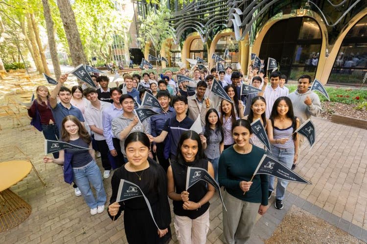 Group of students awarded the Chancellor's Scholarship stand holding pennant flags