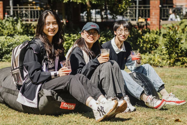 Three students sitting on the lawn at Orientation week