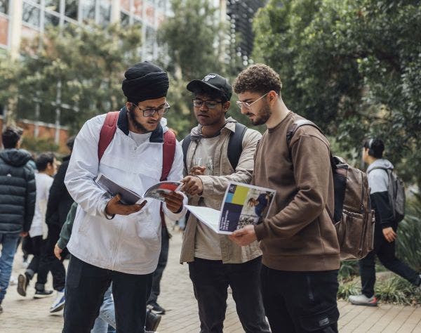 3 students reading a course guide