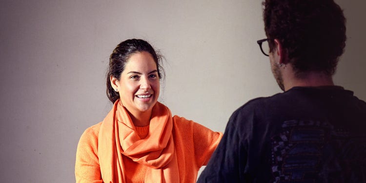 Zoyka Aguayo, speaking with a person whose back is turned to the camera.