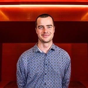 Young man with short hair wearing colourful shirt.