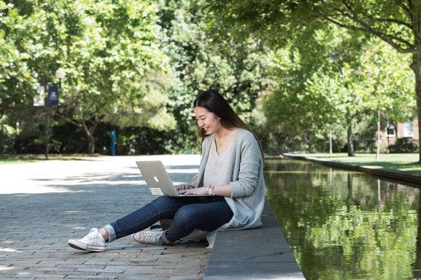 female students sits next to the pong at South Lawn on her laptop
