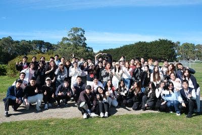 A large group of students outdoors, smiling at the camera.