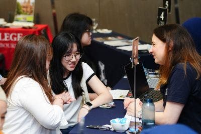 Two students asking staff questions at the event.