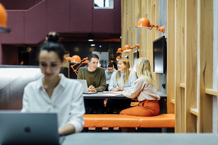 three people studying in the Arts West building with one person studying on their laptop in both the foreground and background
