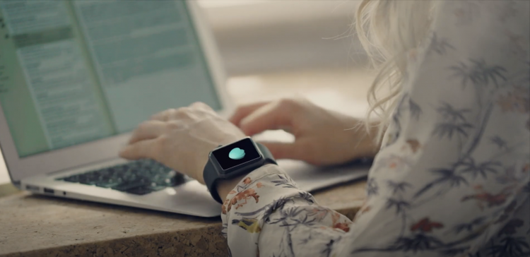 Close up image of person's smart watch while they use a laptop computer