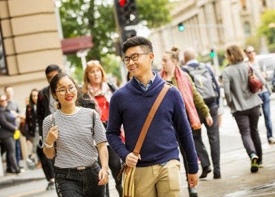 Two students walk together on a crowded city street