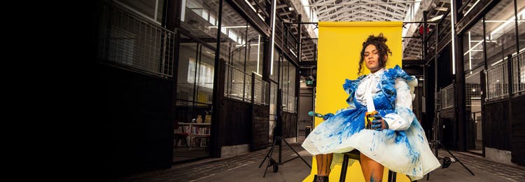 Student holding a palette in front of paintings