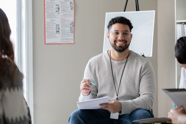 A male social worker sitting with a clipboard.
