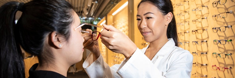 woman putting glasses on another woman