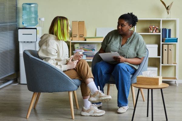 A female social worker speaking with a teenage girl.