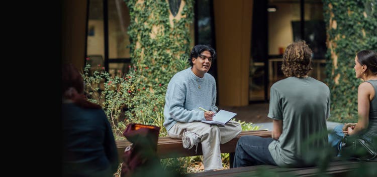 Three students sitting on benches