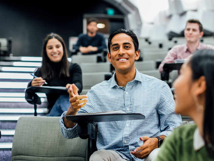 Student sits engaged in a lecture theatre with peers.