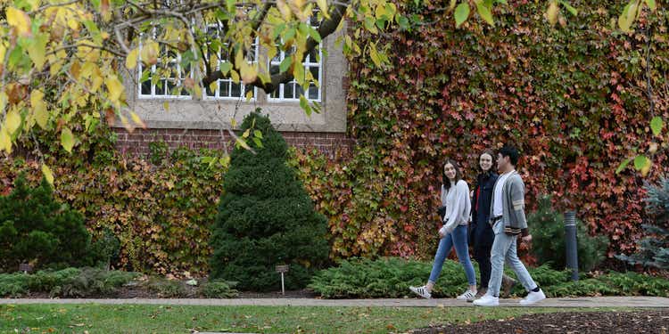 Three students walking across leafy campus