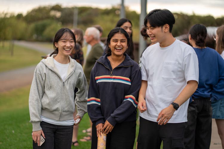 Three Hansen Scholars stand together, laughing, outdoors