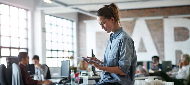Woman sitting on a table holding a tablet.