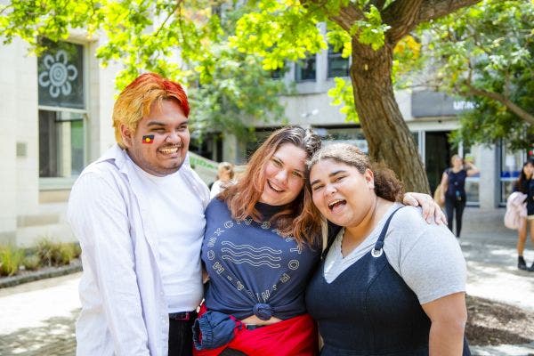 Three students smiling on campus